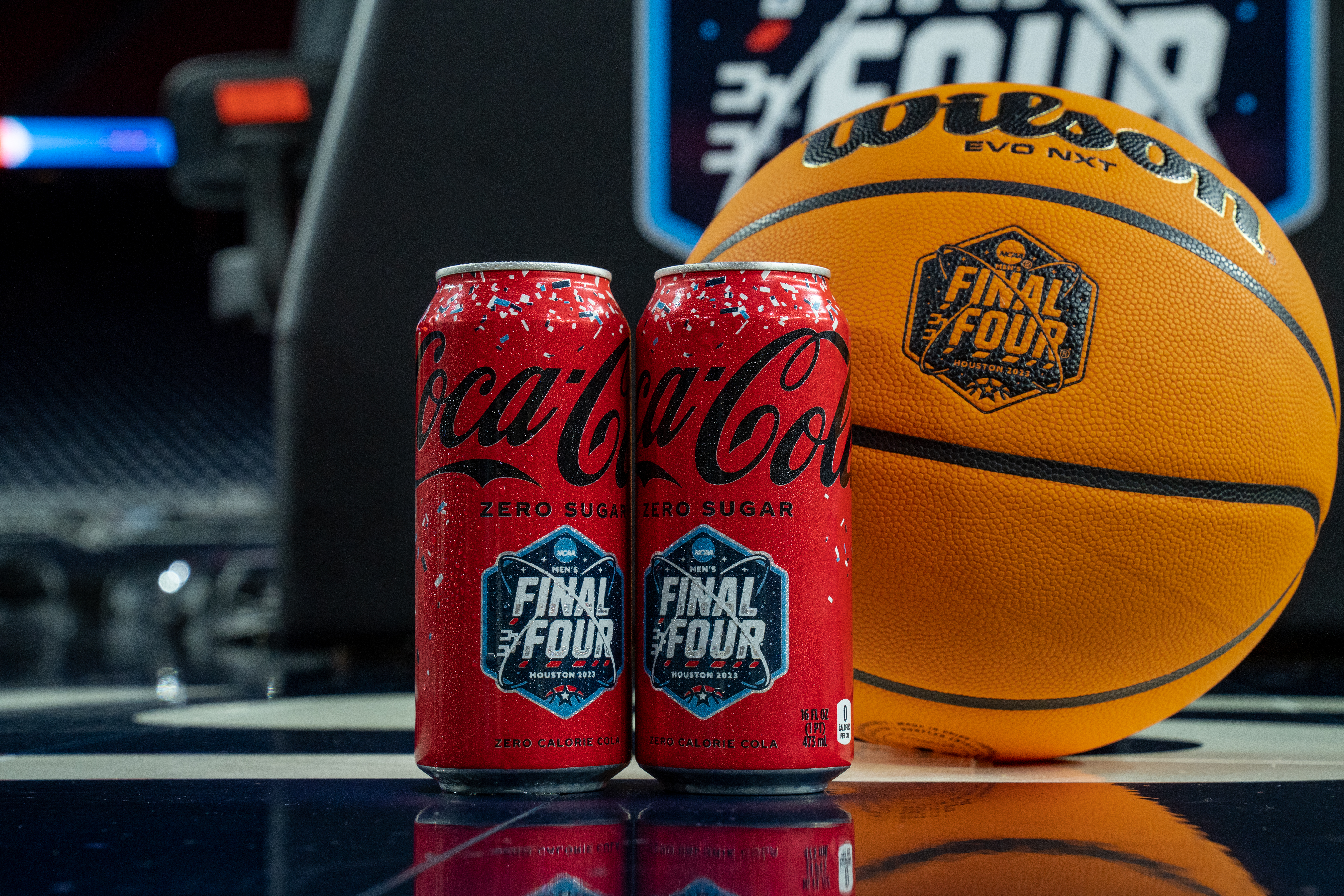 NCAA branded Coca-Cola Zero Sugar cans reflect on the court in front of a Final Four basketball