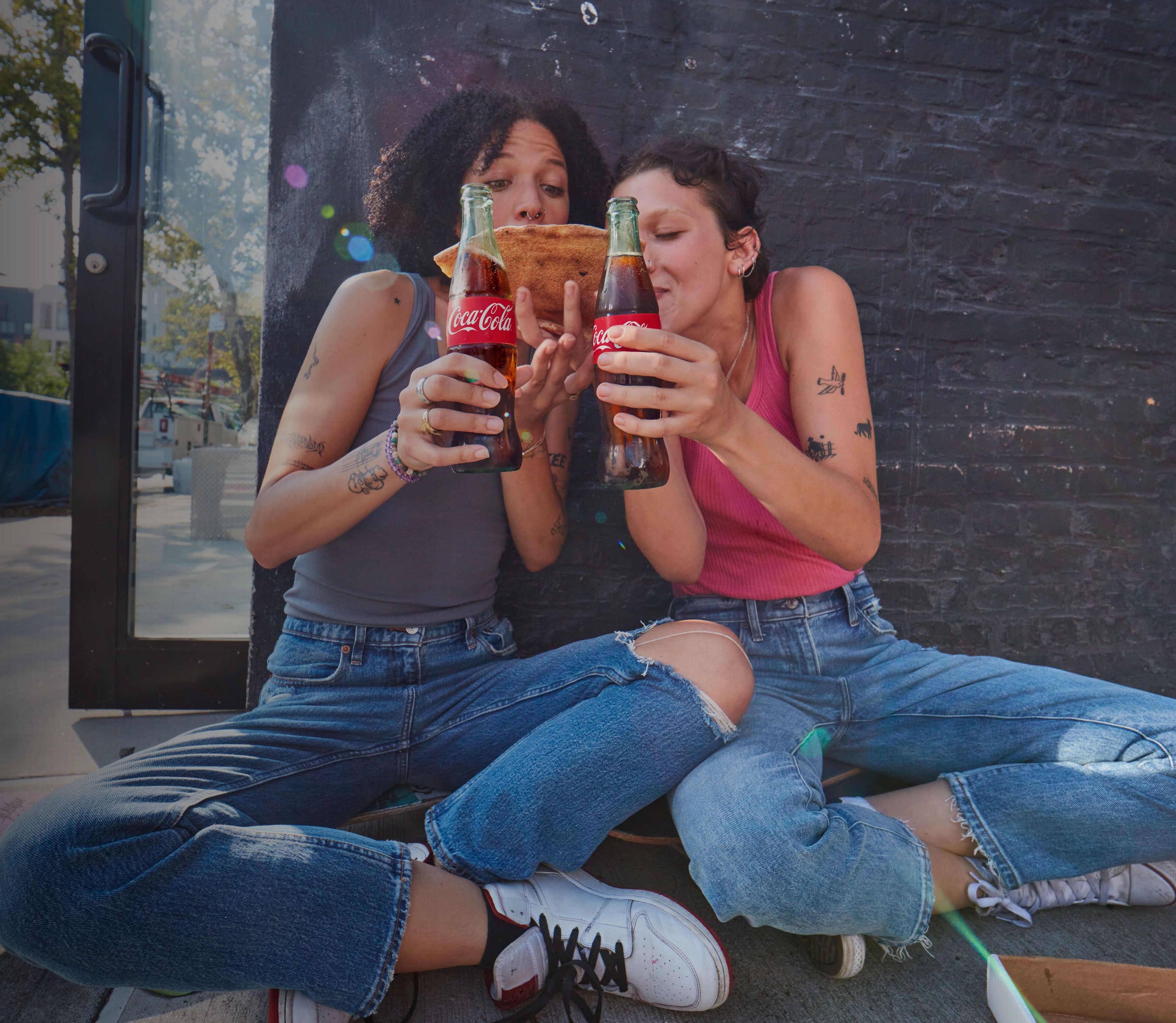 Two women enjoying pizza and Coca-Colas