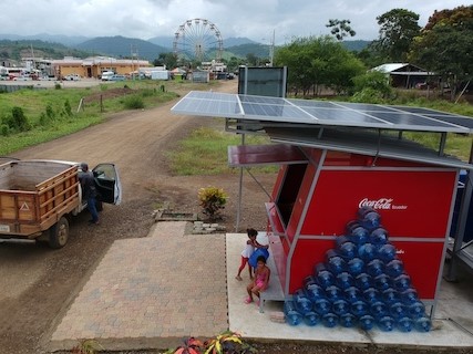 Coca-Cola stand in a local community with a ferris wheel & buildings in the background