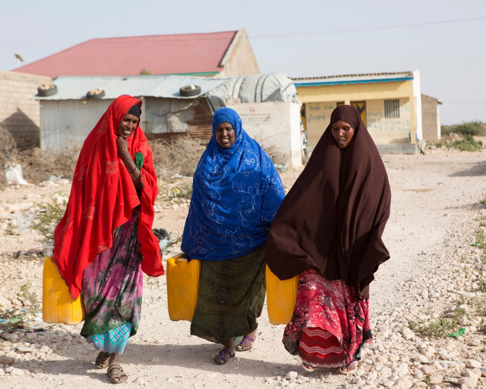 Three African women conversing & walking
