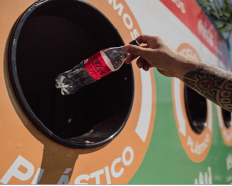 A plastic bottle is placed in a Coca-Cola recycling bin