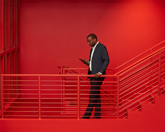 A man in a suit standing on red stairs reading his phone